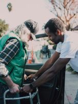 Man Assisting Person with Walker