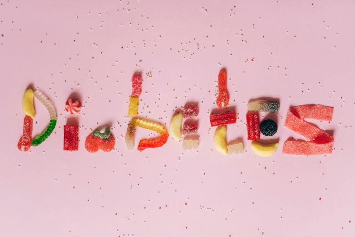 Candies shaped to spell diabetes on a pink background, highlighting sugar intake